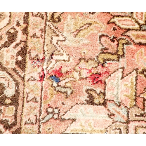 1286 - A large early 20th century Persian Heriz carpet with geometric motifs on a pink ground, made in Iran... 