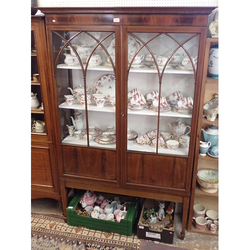 1328 - An Edwardian mahogany display cabinet with a pair of pointed arch glazed doors on slender supports, ... 