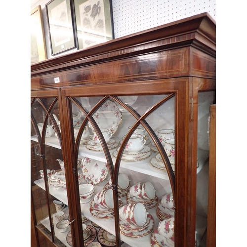 1328 - An Edwardian mahogany display cabinet with a pair of pointed arch glazed doors on slender supports, ... 