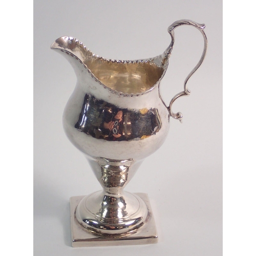 319 - A George III silver cream jug with punched decoration to rim and square pedestal foot, London 1784, ... 