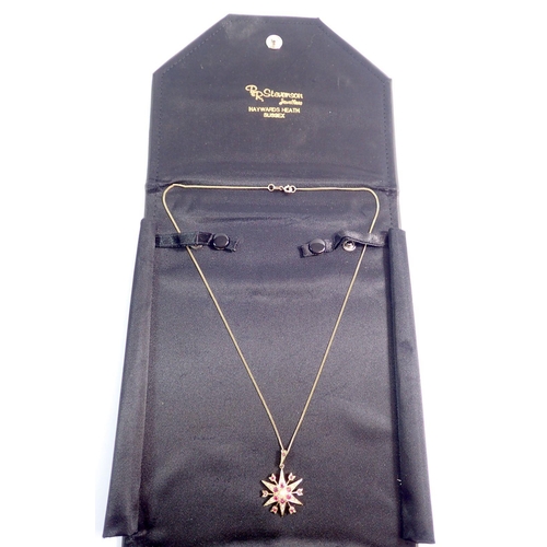 384 - A 9 carat gold star form pendant set rubies and seed pearls on 9 carat gold chain, pendant 2.5cm dia... 