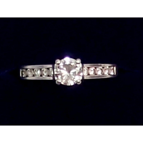 442 - A platinum ring set central diamond flanked by ten diamonds inset to shoulders, size M, 5.5g