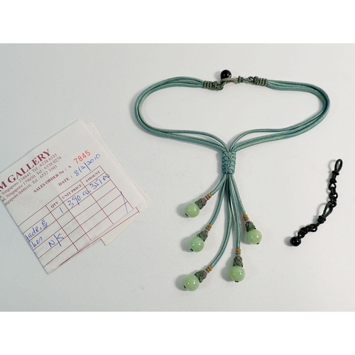 568 - A green silk multi strand necklace with five jade beads, boxed