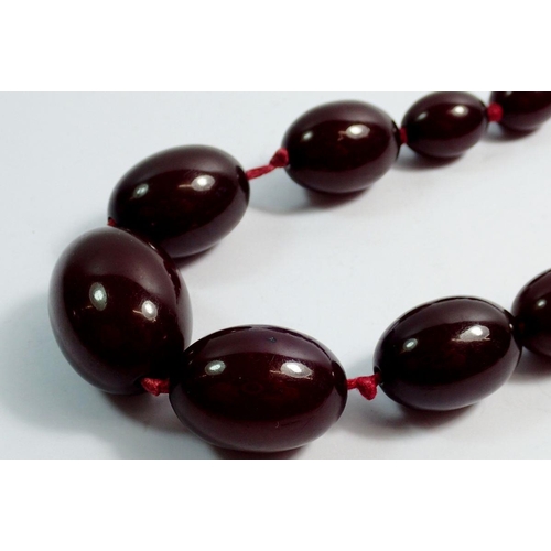 636 - A cherry amber necklace, largest bead 3cm wide, 52g