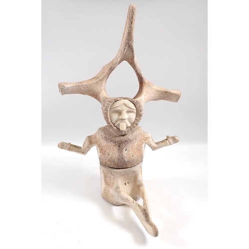 831 - An Inuit carved whale vertebrae sculpture of a seated man, 30cm tall