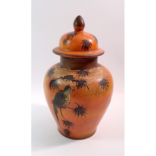 95 - A studio pottery jar and cover in burnt orange decorated bird and butterflies, 30cm tall