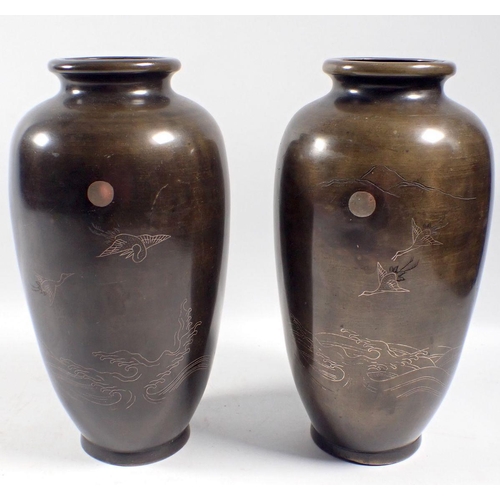 956 - A pair of Japanese Meiji period bronze vases with silver inlaid decoration of cranes flying over the... 