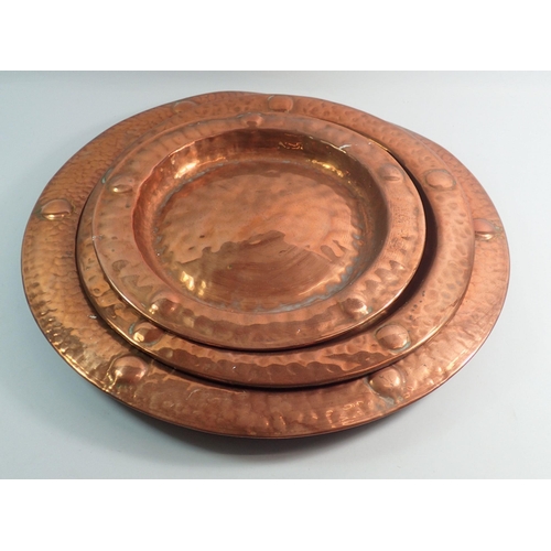 1090 - A set of three copper embossed circular dishes, largest 43cm