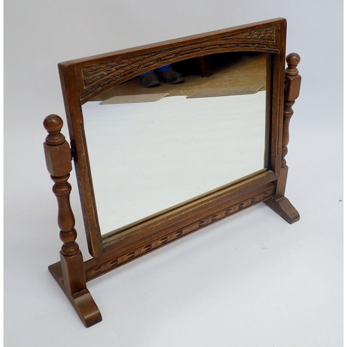 1111 - An oak swing toiletry mirror with carved decoration, 60cm wide