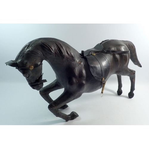 1113 - An early 20th century large leather covered bowing horse, 62cm long