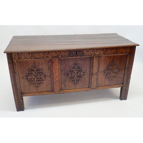 1132 - An 18th century oak coffer with carved lozenge decoration to triple panel front, 135cm wide