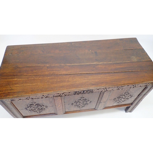 1132 - An 18th century oak coffer with carved lozenge decoration to triple panel front, 135cm wide