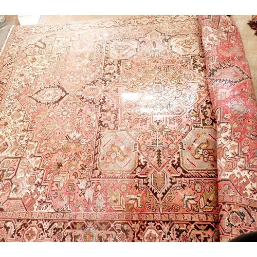 1141 - A large early 20th century Persian Heriz carpet with geometric motifs on a pink ground, made in Iran... 