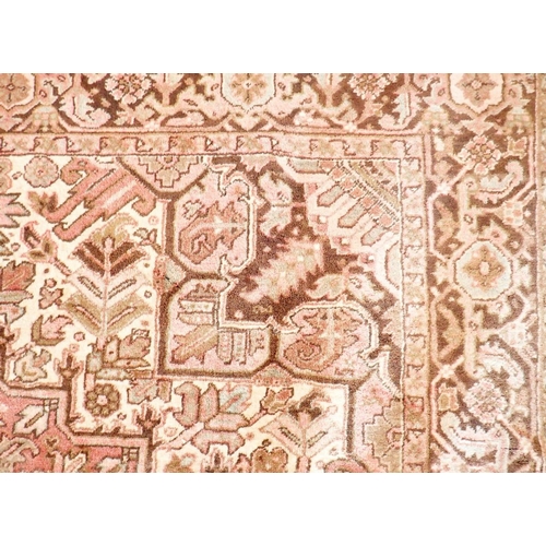 1141 - A large early 20th century Persian Heriz carpet with geometric motifs on a pink ground, made in Iran... 