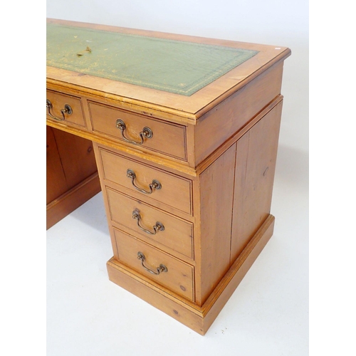 1144 - A stained pine twin pedestal desk with inset leather top and nine drawers, 126cm wide