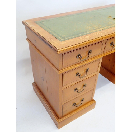 1144 - A stained pine twin pedestal desk with inset leather top and nine drawers, 126cm wide