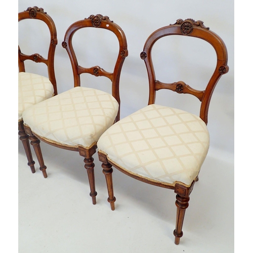 1331 - A set of four Victorian walnut dining chairs with carved backs and fluted tapered supports