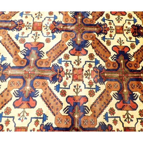 1365 - A Turkmanistan Persian large carpet with geometric and stylised floral decoration on a cream ground ... 