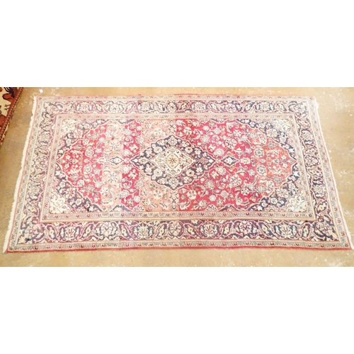 1423 - A Persian rug with blue medallion on a red ground 259 x 141cm