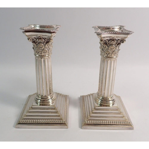 243 - A pair of Victorian silver plated corinthian column candlesticks, 16cm tall