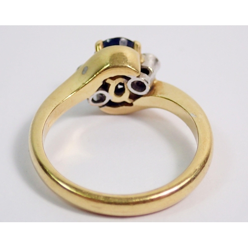 383 - An 18 carat gold ring crossover set oval cut sapphire flanked by two small diamonds, size L to M, 5.... 