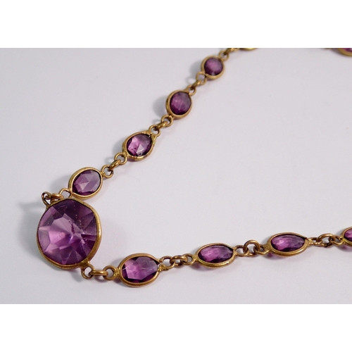 452 - An Edwardian long amethyst paste and yellow metal necklace with single spare stone, 140cm