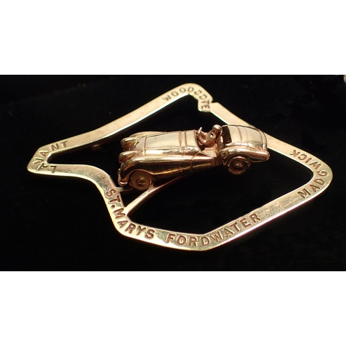 477 - An unusual 9 ct gold motor racing Stirling Moss brooch with racing car mounted on Goodwood race trac... 