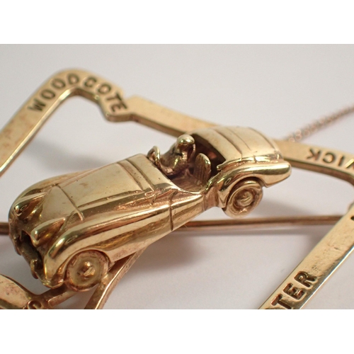 477 - An unusual 9 ct gold motor racing Stirling Moss brooch with racing car mounted on Goodwood race trac... 