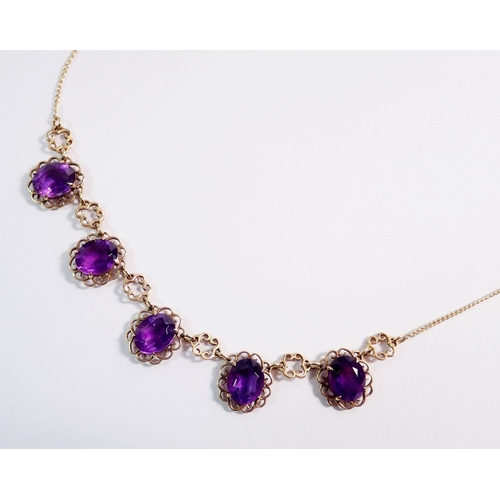 478 - A 9 carat gold necklace suspended five oval cut amethysts within scrollwork surrounds, 44cm, 9g