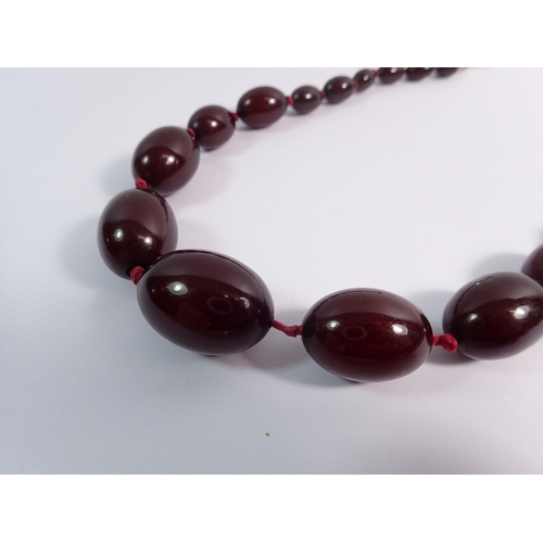 559 - A cherry amber necklace, largest bead 3cm wide x 2cm, 58cm total length of necklace, 52g