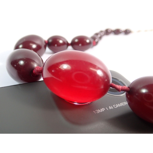 559 - A cherry amber necklace, largest bead 3cm wide x 2cm, 58cm total length of necklace, 52g