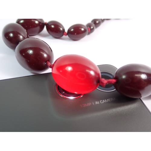 559 - A cherry amber necklace, largest bead 3cm wide x 2cm, 58cm total length of necklace, 52g