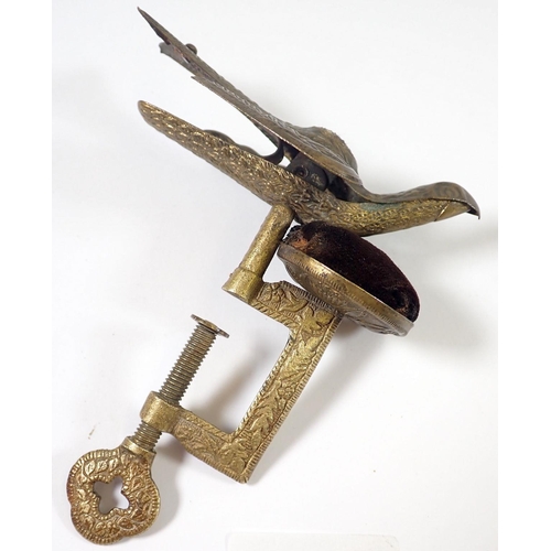 942 - An antique brass sewing clamp with pin cushion and bird surmount, 13cm tall