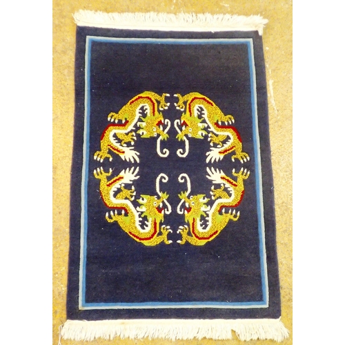 1142 - A Chinese navy blue small rug decorated dragons, 93 x 63cm