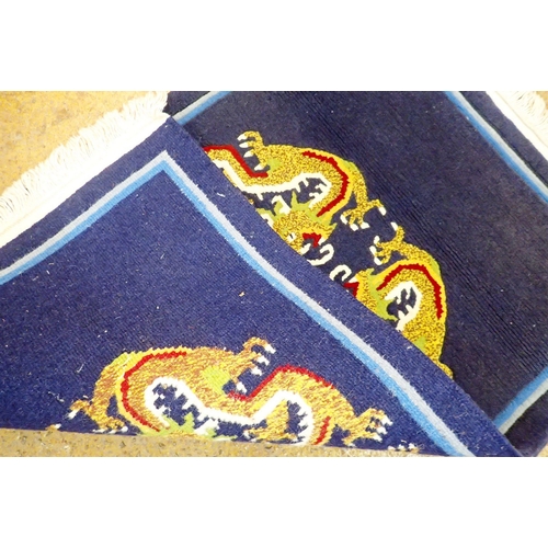 1142 - A Chinese navy blue small rug decorated dragons, 93 x 63cm