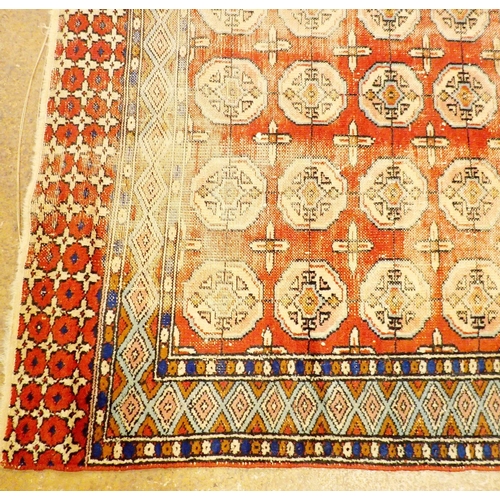 1150 - An antique Turkoman rug with four rows of guls on a red ground within blue borders, 175 x 119cm