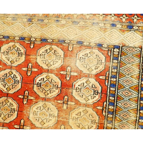 1150 - An antique Turkoman rug with four rows of guls on a red ground within blue borders, 175 x 119cm