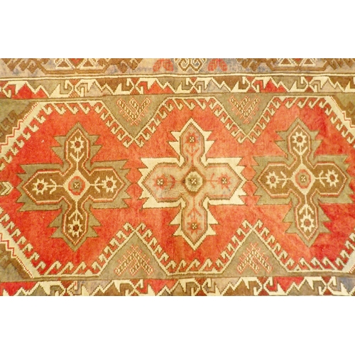 1152 - An Afghan style rug with three geometric motifs on a red ground within multiple borders, 194 x 121cm