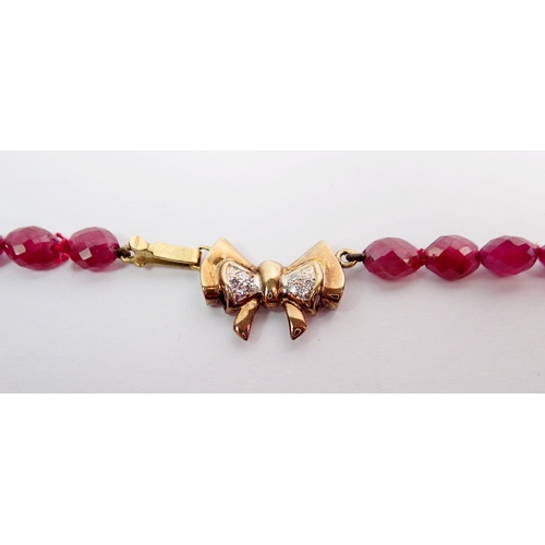 384 - A ruby bead necklace with 9 carat and chip diamond bow clasp, 40cm long