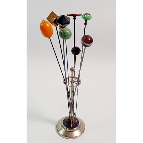 421 - A collection of beaded hat pins in silver plated circular stand including amber