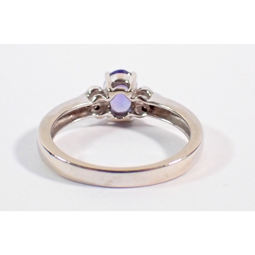 252 - A 14 carat white gold ring set oval cut tanzanite flanked by six small diamonds, size O, 3.5g