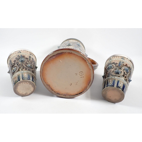 17 - A Doulton Lambeth stoneware tall jug, 25cm tall and two tumblers with applied decoration and silver ... 