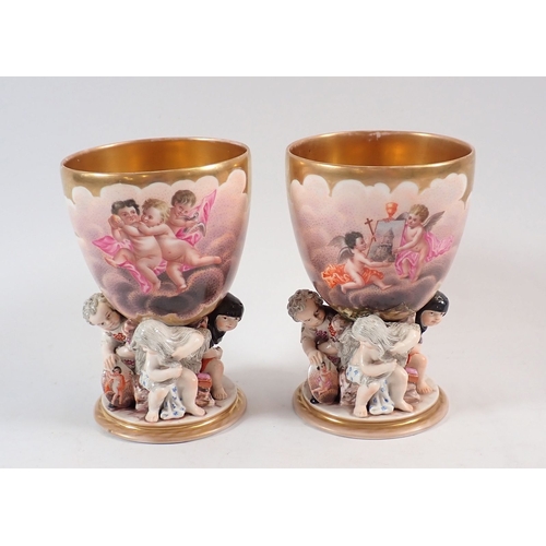 132 - A pair of 19th century Berlin gilt porcelain goblets painted reserves of cherubs in the clouds on fi... 
