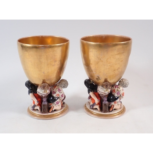 132 - A pair of 19th century Berlin gilt porcelain goblets painted reserves of cherubs in the clouds on fi... 