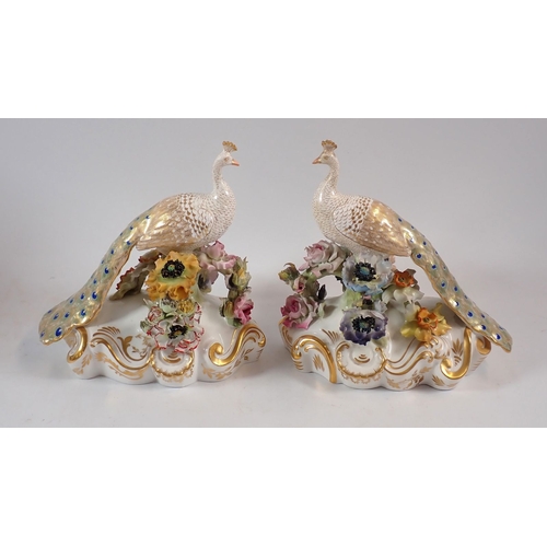 147 - A Royal Crown Derby pair of peacocks on floral bases, 18cm high, one signed J.Brown, one signed V.E.... 