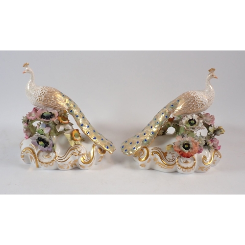 147 - A Royal Crown Derby pair of peacocks on floral bases, 18cm high, one signed J.Brown, one signed V.E.... 