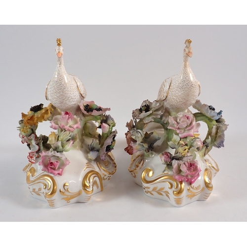 147 - A Royal Crown Derby pair of peacocks on floral bases, 18cm high, one signed J.Brown, one signed V.E.... 