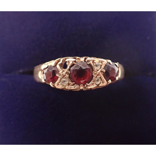 377 - A 9 carat gold three stone garnet ring with diamond accents, one deficient, size T, 2.1g