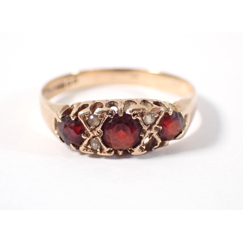 377 - A 9 carat gold three stone garnet ring with diamond accents, one deficient, size T, 2.1g