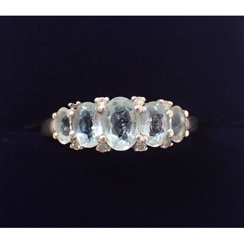 388 - A 9ct gold five stone aquamarine ring with chip diamond accents, size U, 2.7g